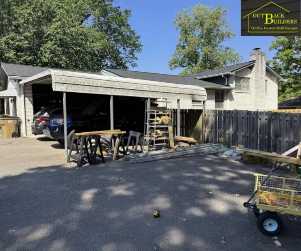 A spacious, modern metal carport with a dark gabled roof and white support columns.
