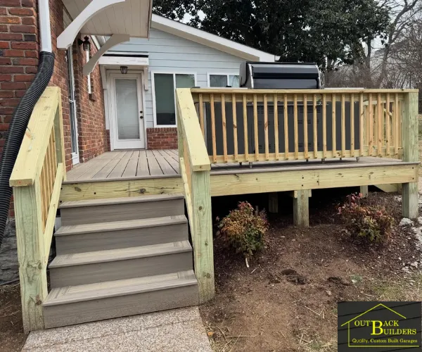 A completed outdoor composite deck with gray planks and light wood railings.